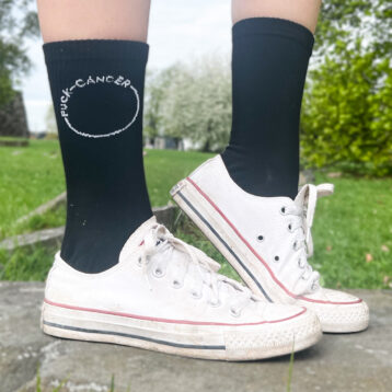 Bilde av føtter med conversesko og Fuck Cancer-sokker på.