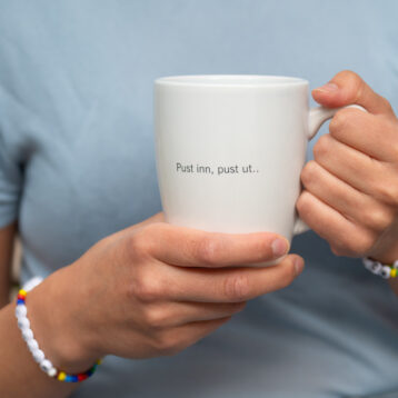 Bilde av person som holder hvit kaffekopp.
